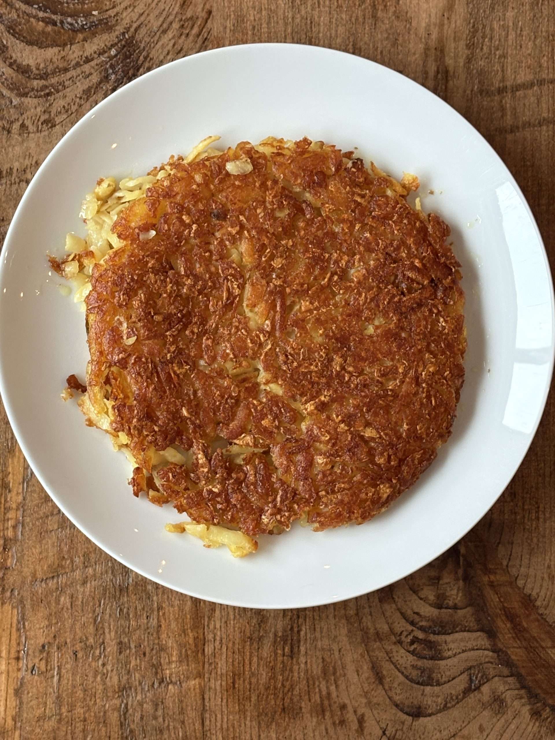 12 Easy Swiss Recipes You Can Try at Home 3 Crispy Swiss potato rosti on a white plate.