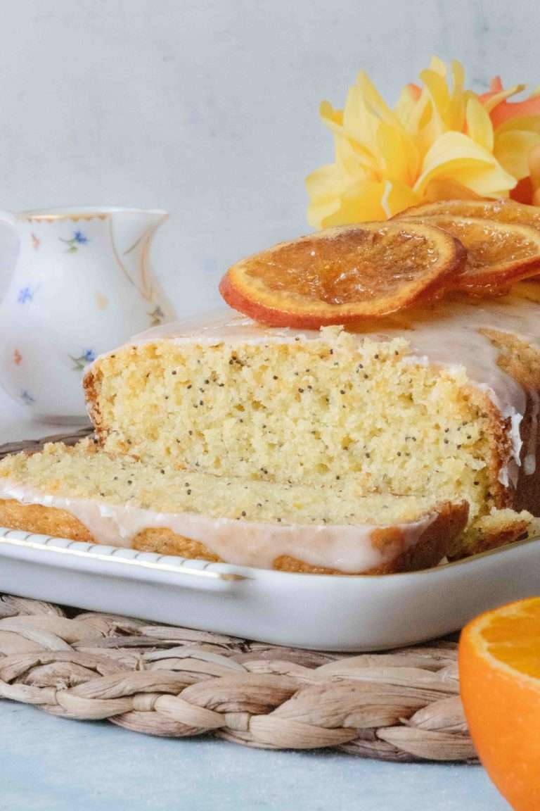 Close-up of a cross section of an orange poppy seed loaf showing the tender crumb and poppy seed specks.