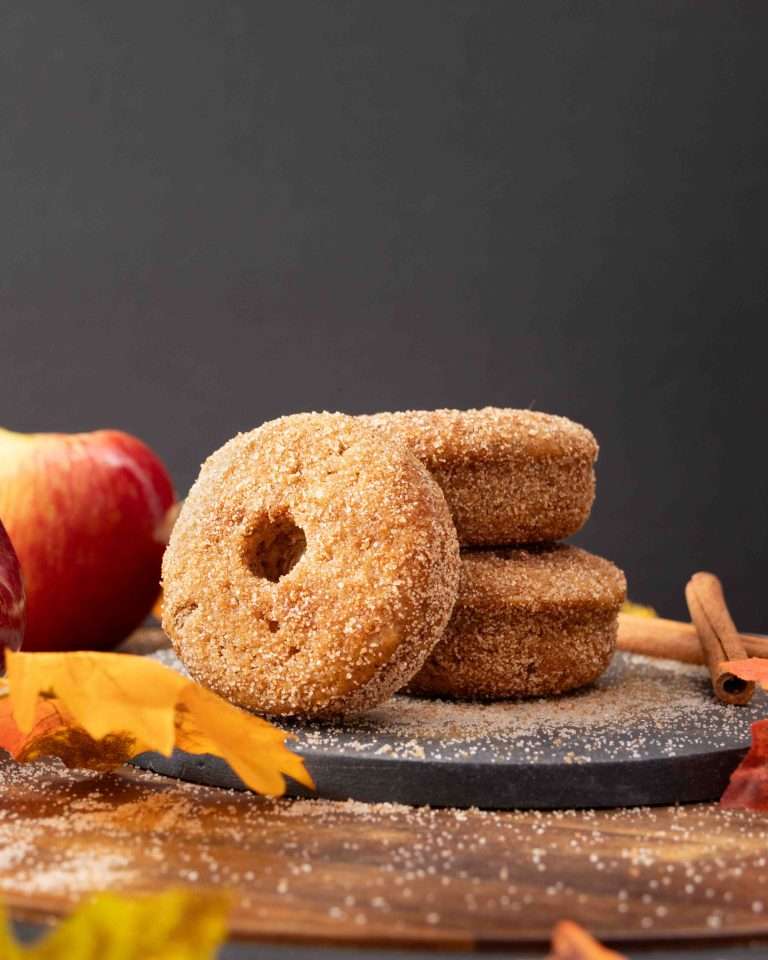 Baked apple cider donuts stacked with cinnamon sugar coating.