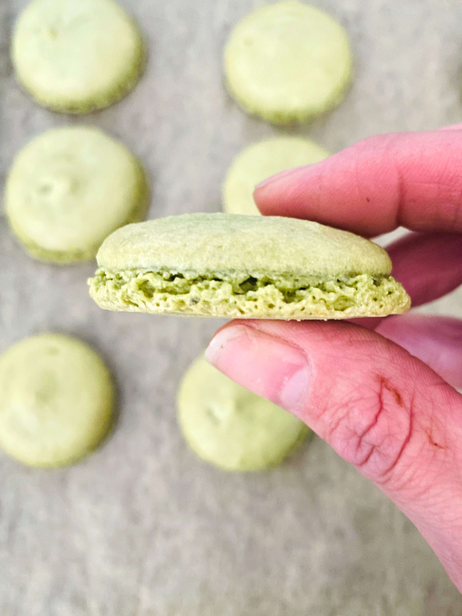 Macaron shell being held to show the bottom raised "foot"