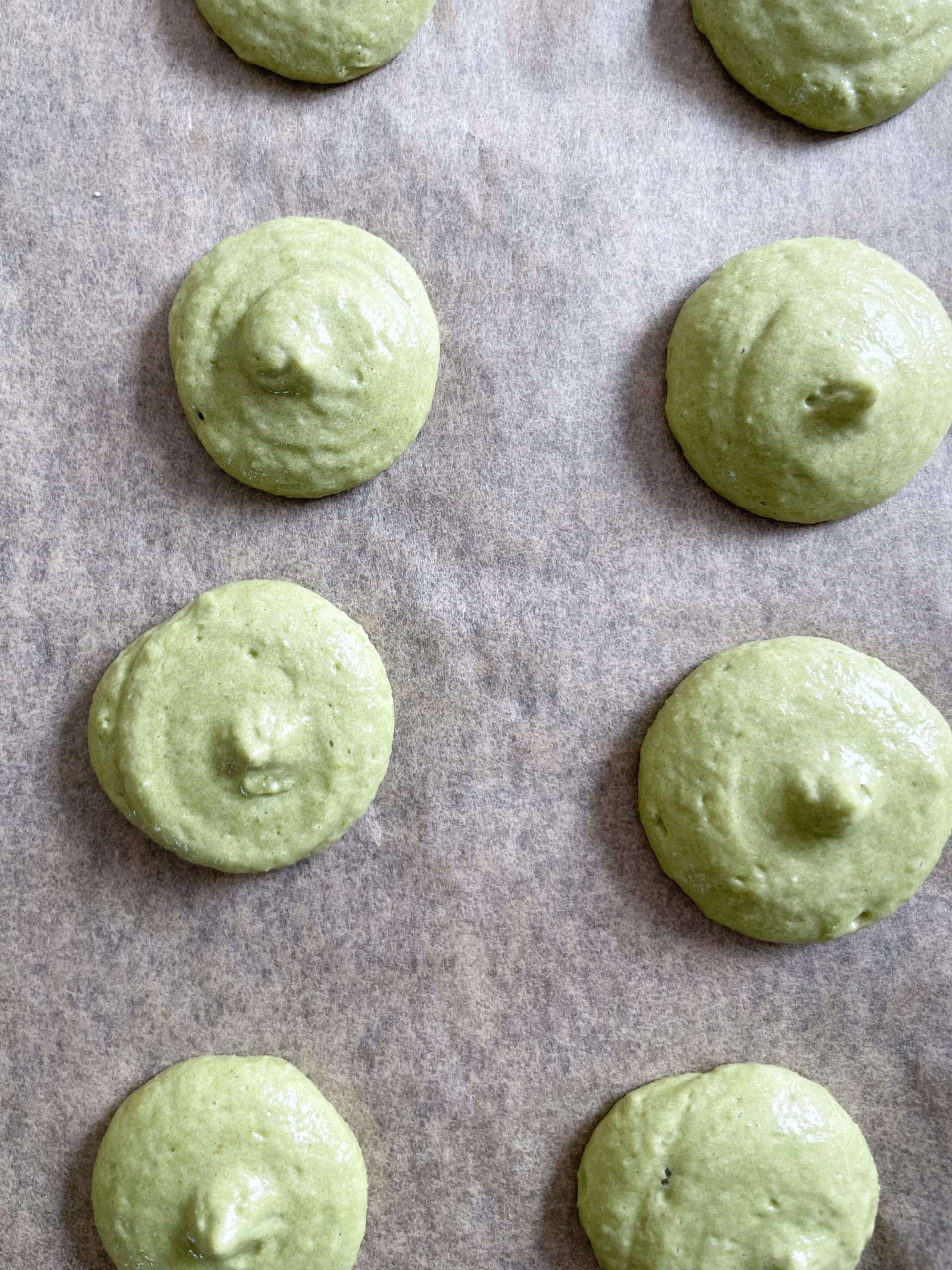 Piped macaron shells on a baking sheet.