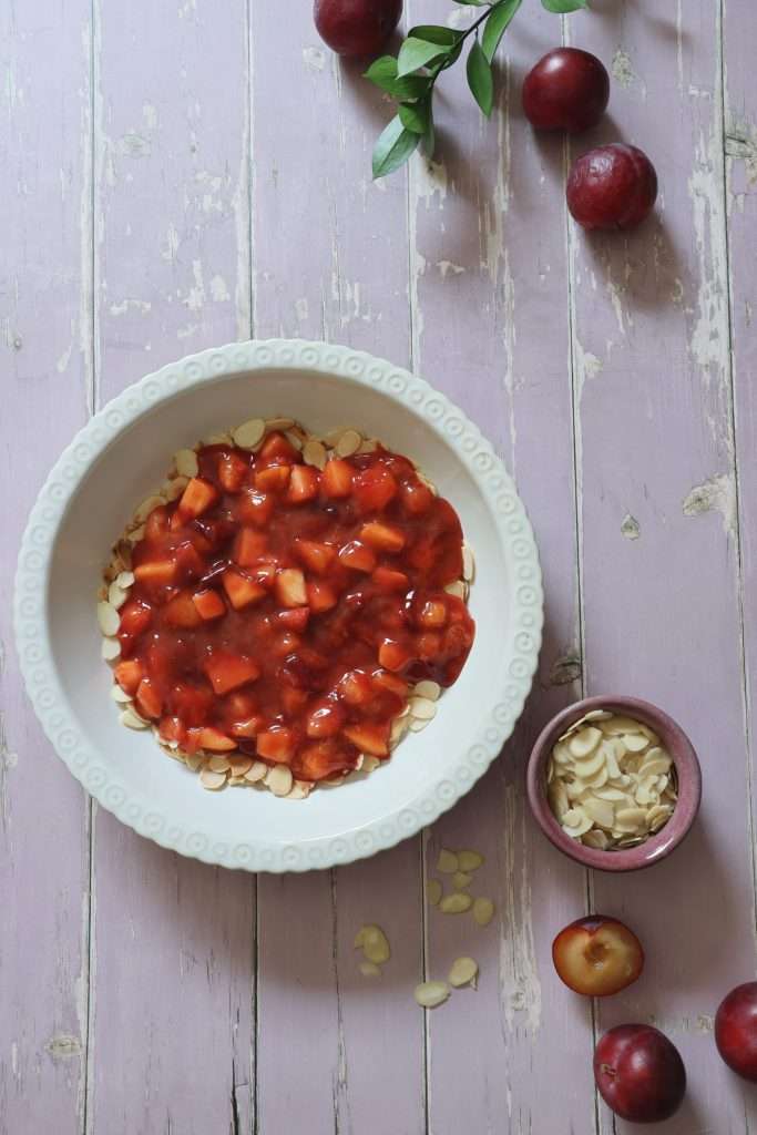 Swiss Plum Meringue (Zwetschgen) with Toasted Almond Base 7 Cooked plums placed atop the toasted almonds in a baking dish for the Swiss plum meringue dessert.