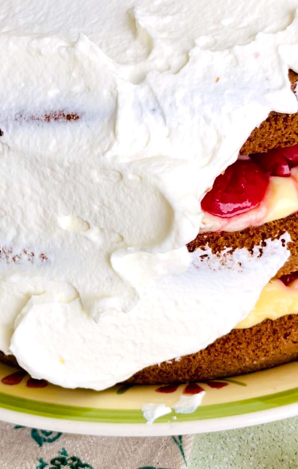 Close-up of the white forest cake layers with juicy cherries visible under the whipped cream topping.