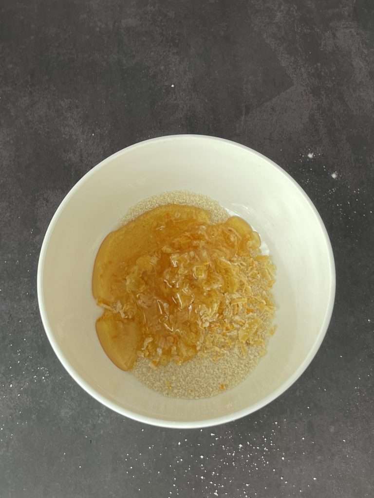 Basler Läckerli (Traditional Swiss Honey Spice Cookies) 15 Honey, lemon and candied citrus in a white mixing bowl which will be added to the flour and spices to make Swiss Basler Lakerli cookies.