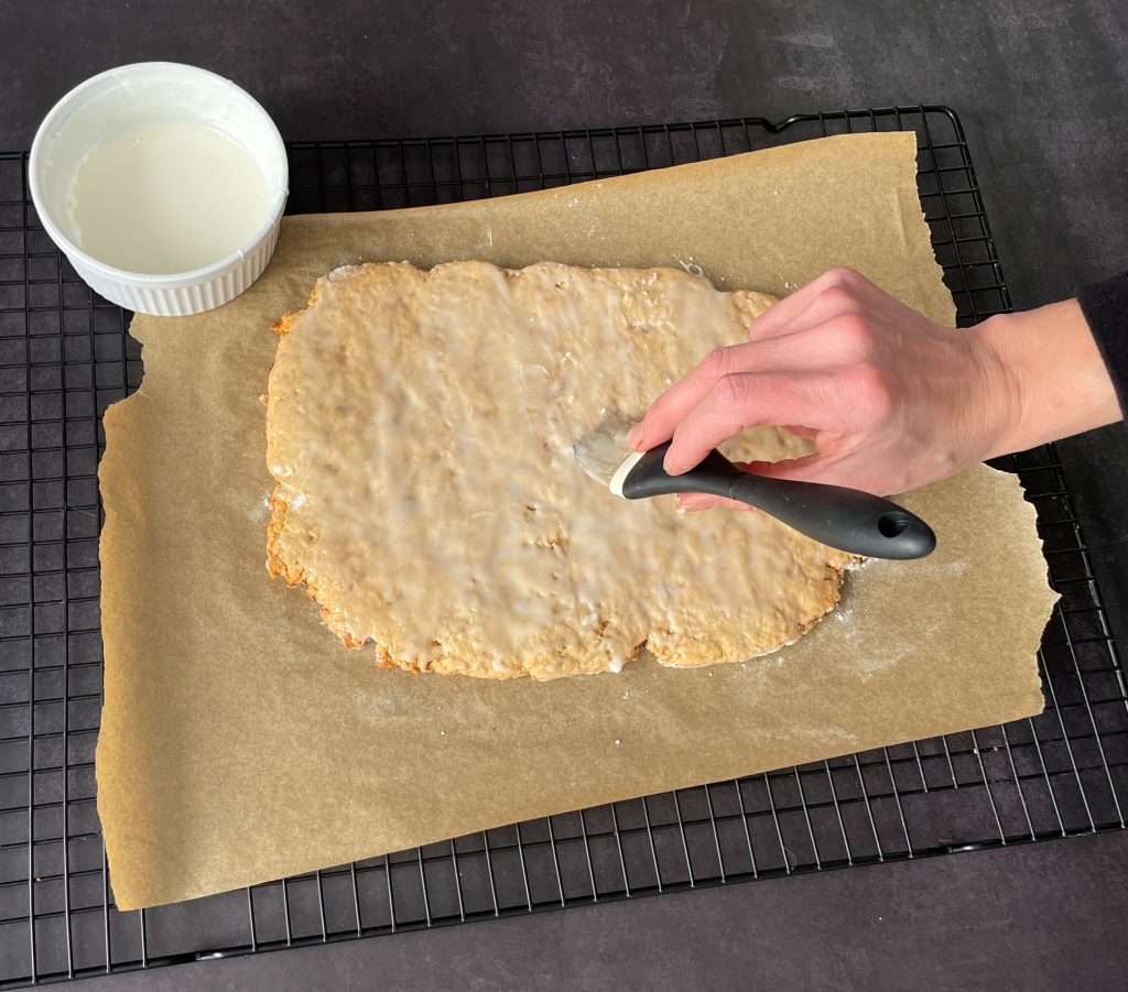 Basler Läckerli (Traditional Swiss Honey Spice Cookies) 19 Baked Basler Lakerli dough being glazed with a sugar glaze.