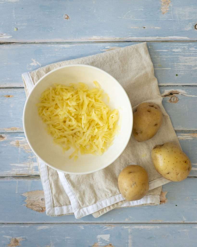 Spring Carrot Rösti Recipe with Lemon and Herbs 19 Grated potatoes in a white bowl.
