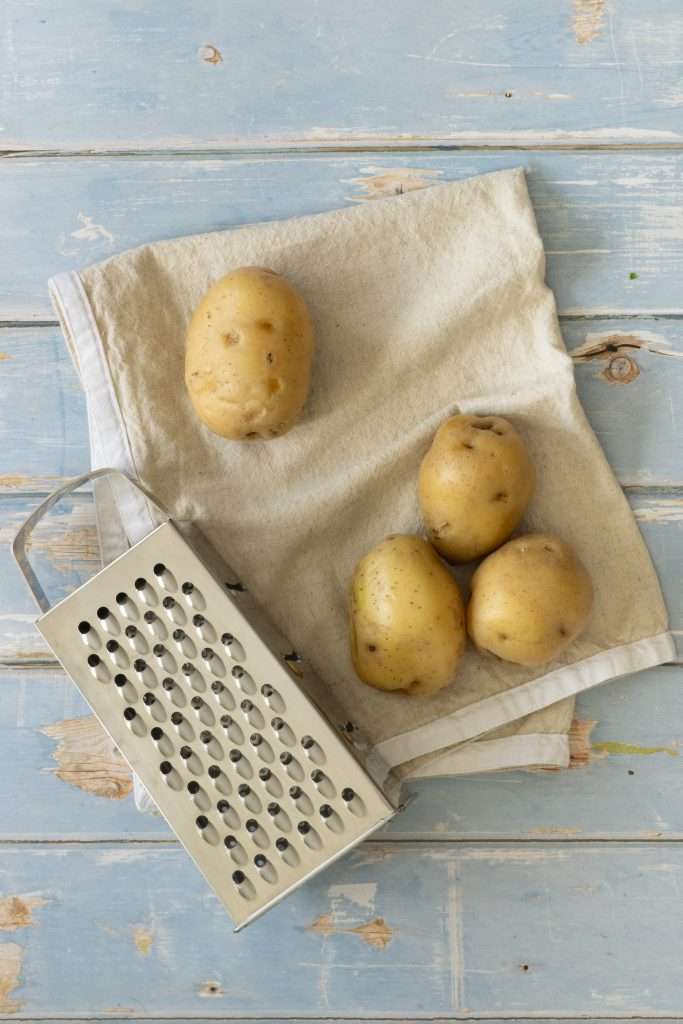 Spring Carrot Rösti Recipe with Lemon and Herbs 17 Parboiled yellow potatoes laying next to a box grater.