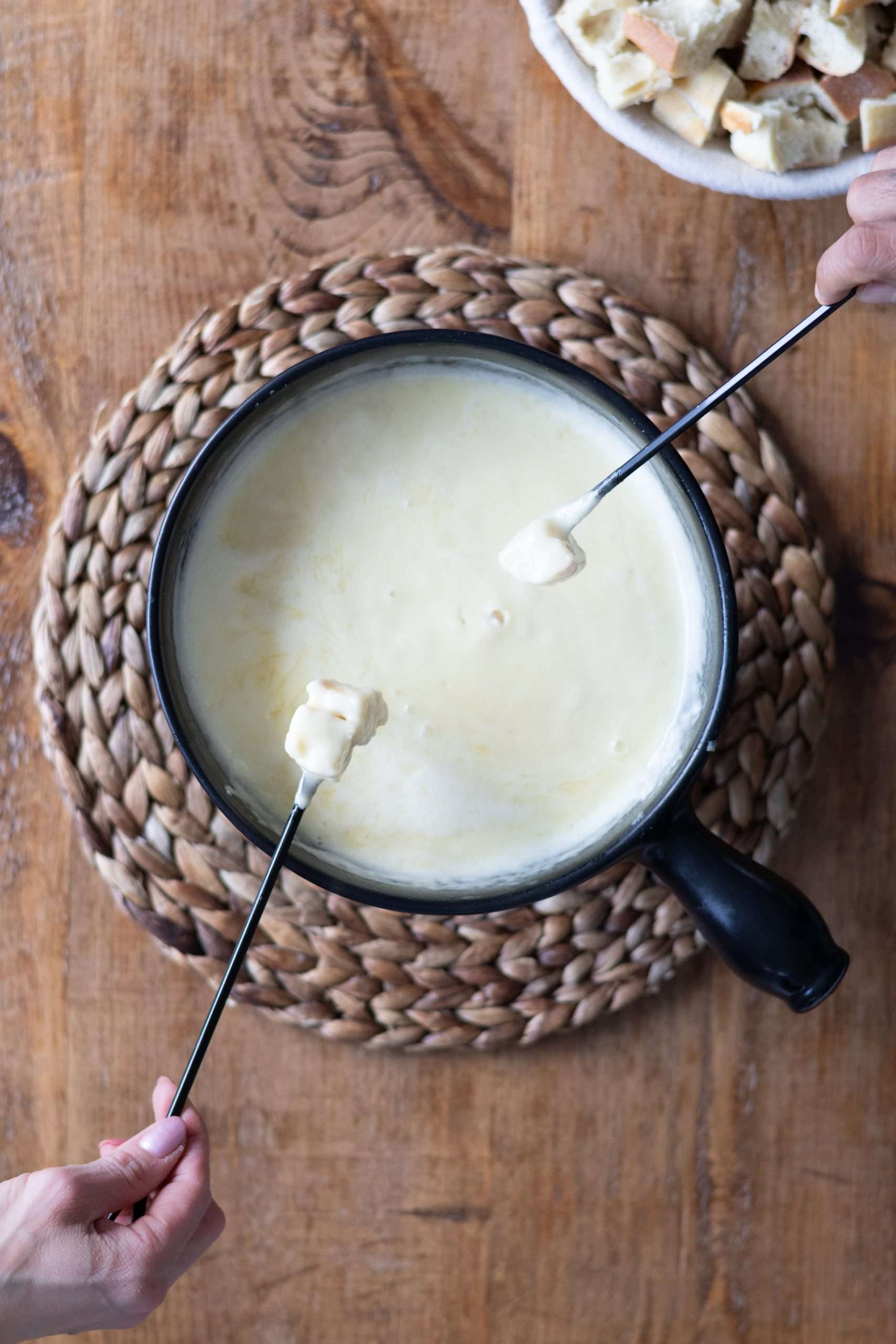 12 Easy Swiss Recipes You Can Try at Home 9 Two pieces of bread being dipped into the pot of cheese fondue.