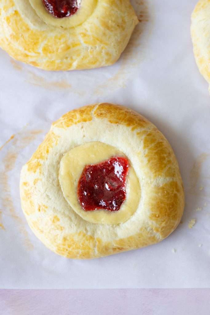 Strawberry Rhubarb Brioche Buns with Baked Vanilla Cream 39 Close-uo of a strawberry rhubarb brioche bun with a vanilla cream and strawberry rhubarb center.
