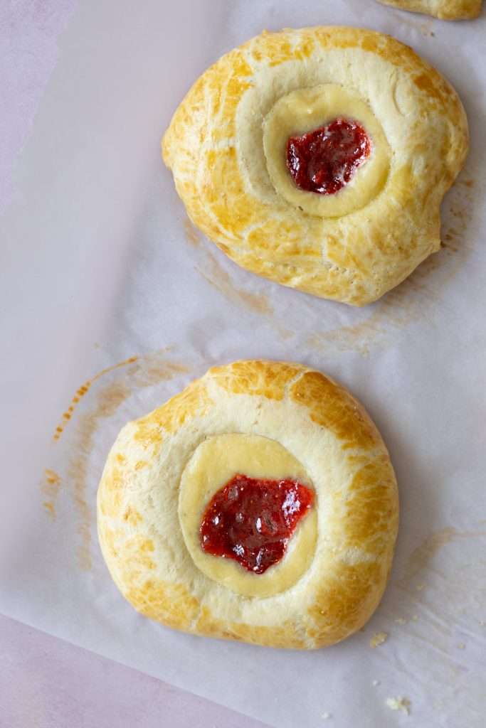 Strawberry Rhubarb Brioche Buns with Baked Vanilla Cream 5 Two strawberry rhubarb brioche buns seen from the top down with their vanilla cream and jam centers.