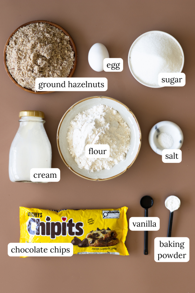 Chocolate hazelnut cake ingredients laid out.  Hazelnut meal, egg, sugar, cream, flour, salt, chocolate chips, vanilla and baking powder.