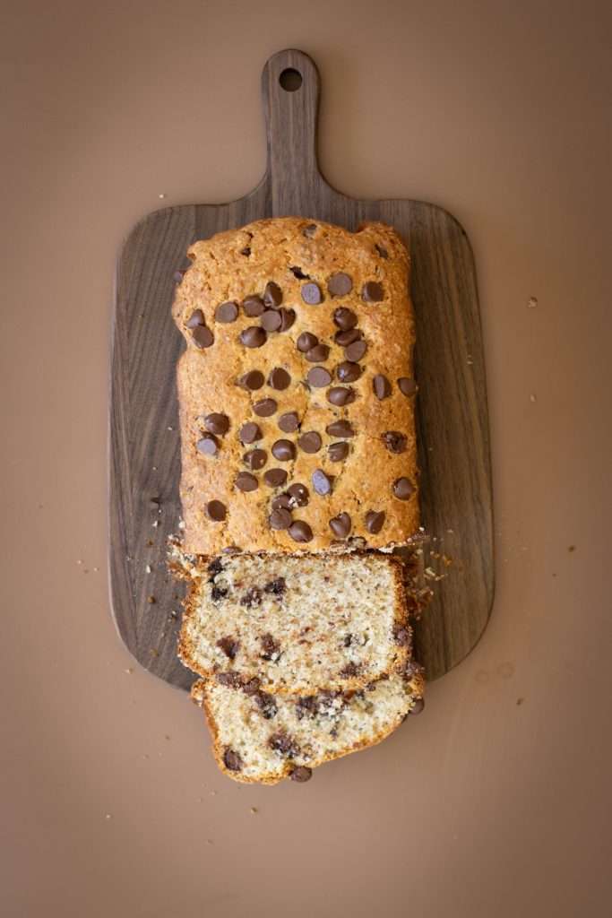 Chocolate hazelnut cake on a wooden board with two slices cut showing the hazelnut crumb and chocolate chips.