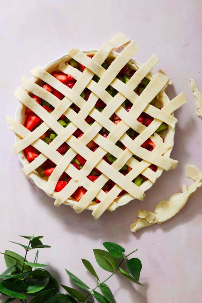 A strawberry rhubarb tart with a latticed top before baking.