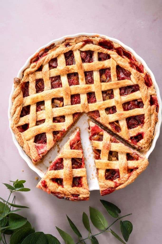 Strawberry rhubarb tart with hazelnut frangipane in a pie dish with two cut slices.