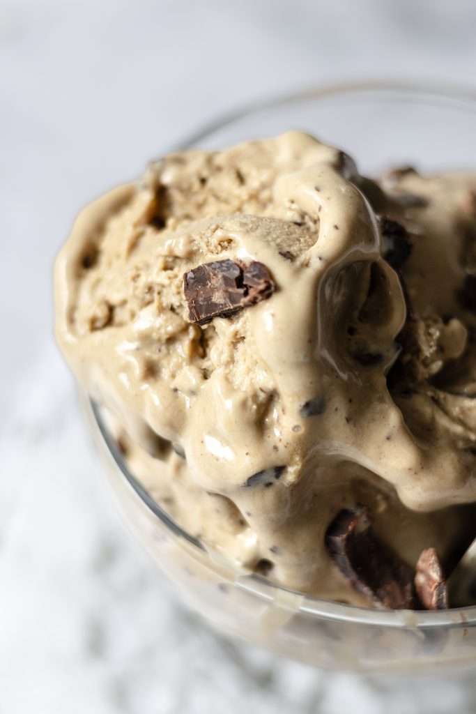 Homemade Coffee Ice Cream with Chocolate & Meringue 23 Coffee ice cream in a glass where the creamy texture and chocolate bits are seen.