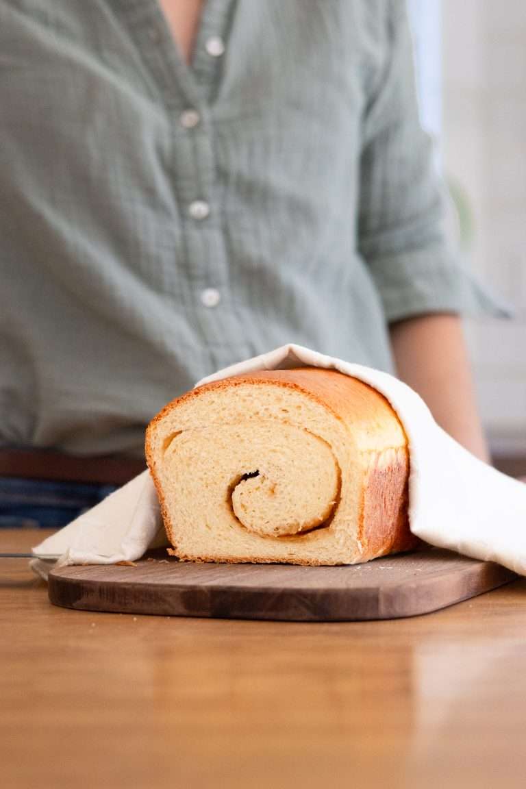 A loaf of maple brioche on a cutting board having been sliced to show the maple swirl.